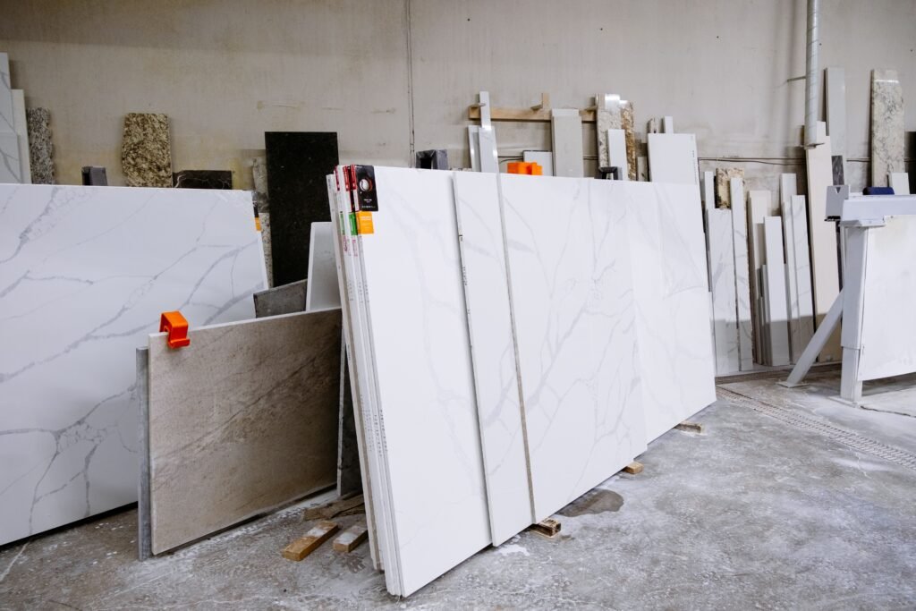Wide view of granite and marble slabs neatly arranged in a factory setting, showcasing variety and texture.