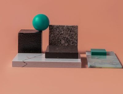 A minimalist geometric arrangement with various textured blocks and a sphere on a peach backdrop.